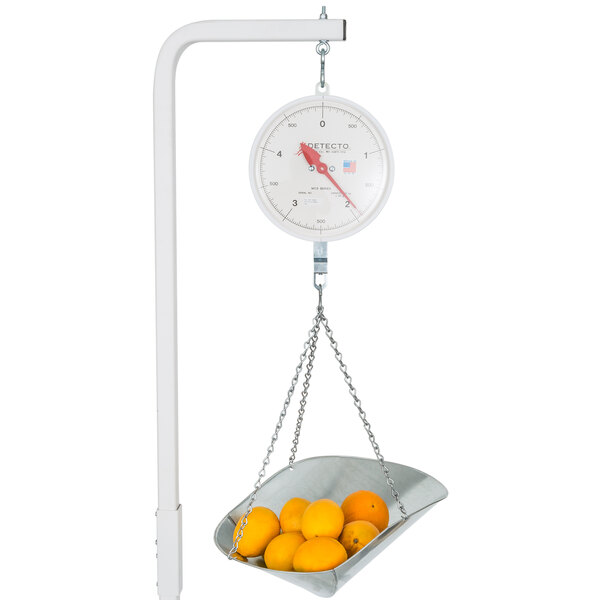 A Cardinal Detecto hanging scoop scale with a bowl of oranges.