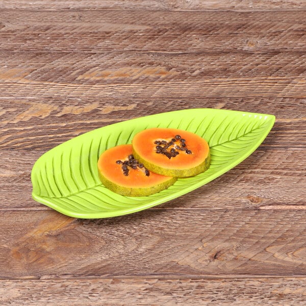 A green Elite Global Solutions Tropicana leaf melamine platter with papaya slices on it.