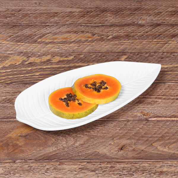 A white Elite Global Solutions Tropicana leaf melamine platter with a plate of fruit on it.