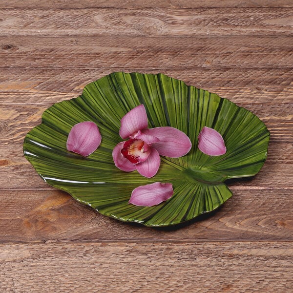 A green leaf shaped Elite Global Solutions melamine plate with pink flowers on it.