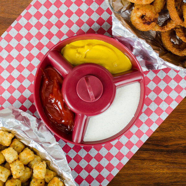 A red polypropylene server with tater tots, onion rings, and red sauce inside.