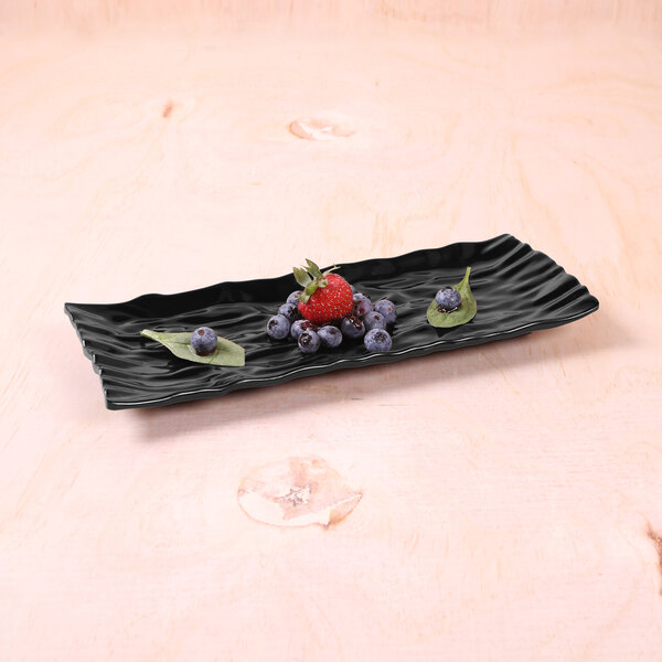 A black rectangular melamine tray with berries on it.