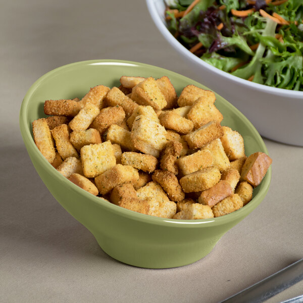 An Elite Global Solutions Weeping Willow green melamine bowl filled with croutons next to a bowl of salad.