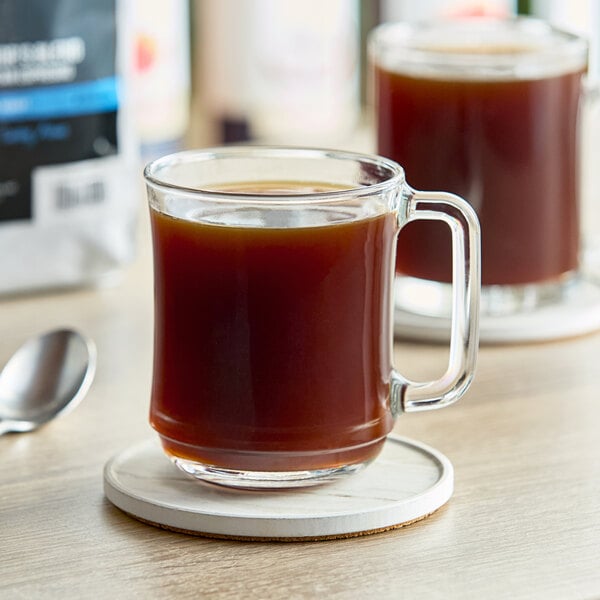 A glass mug of Crown Beverages Emperor's Blend espresso on a wooden coaster.