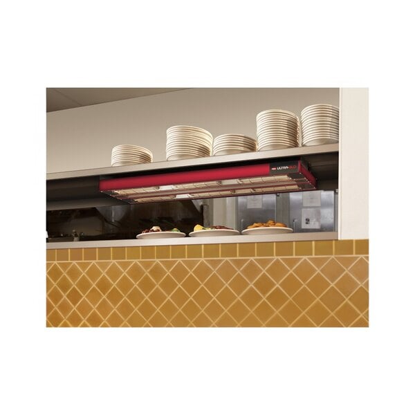 A kitchen counter with Hatco UGA-24D strip warmers on it with white plates.