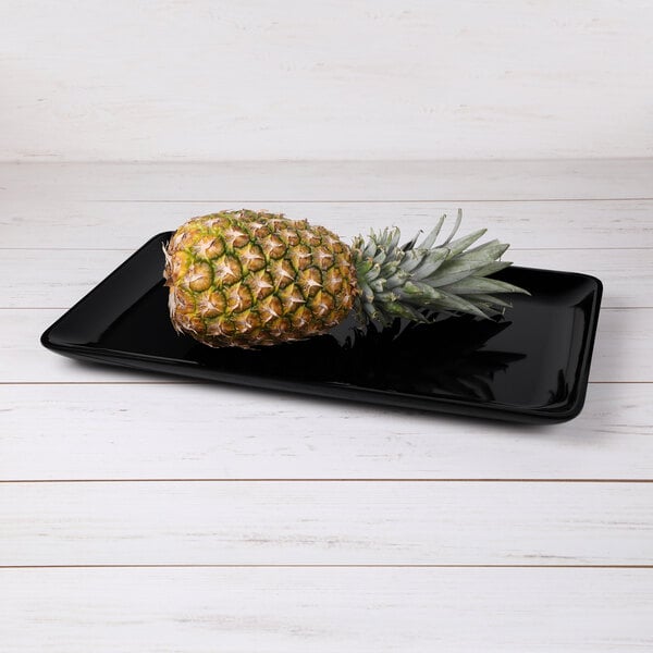 A pineapple on a black rectangular melamine tray.