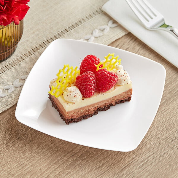 A piece of cake with raspberries and cream on a Fineline white plastic dessert plate with a fork.