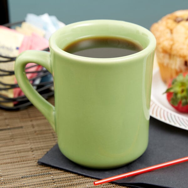 A green Tuxton china mug with a brown drink on a table with a napkin.