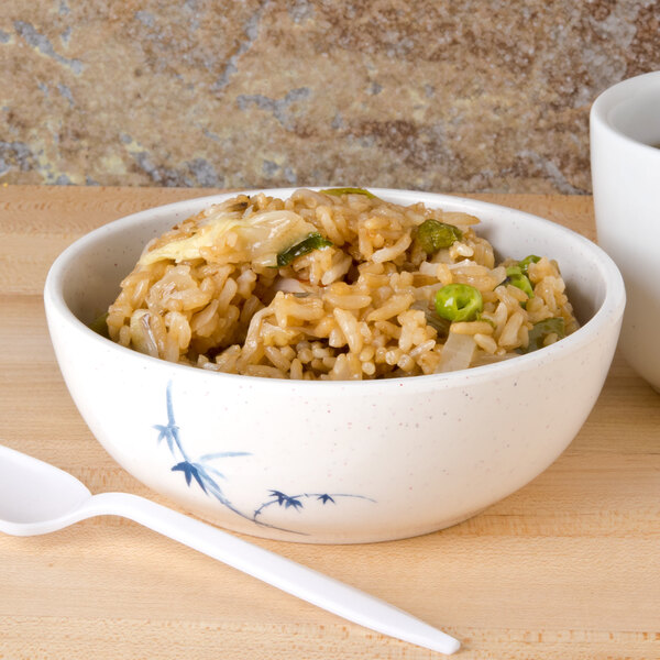 A blue Thunder Group Blue Bamboo melamine bowl filled with rice next to a white spoon on a white table.