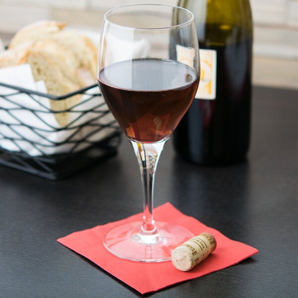 A Chef & Sommelier Exalt wine glass filled with wine sits on a table next to a bottle of wine.