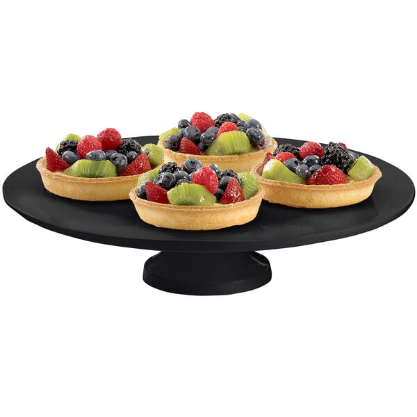 A black Tablecraft cast aluminum cake stand with fruit on it.