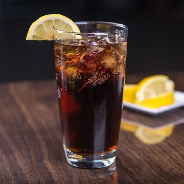 A glass of iced tea with ice and a lemon slice on a table.