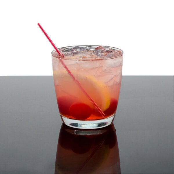 A Arcoroc Excalibur rocks glass filled with a red cocktail and a straw.