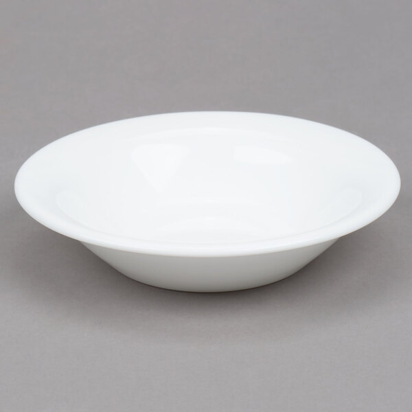 An Arcoroc white opal glass fruit bowl on a gray surface.