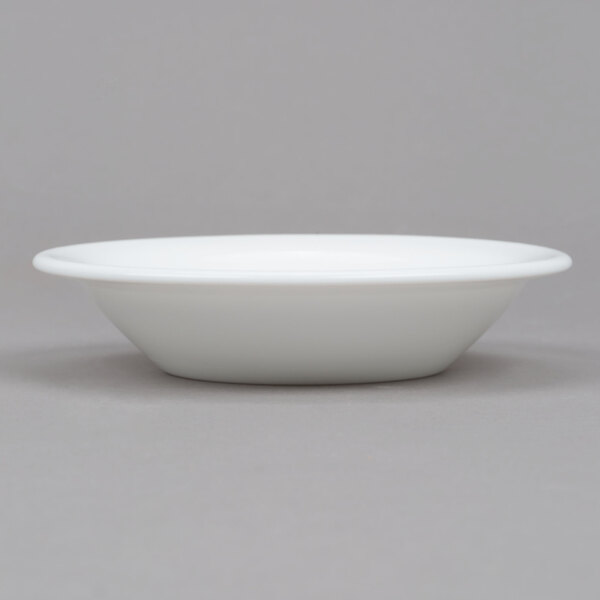 An Arcoroc white opal glass fruit dish on a gray surface.
