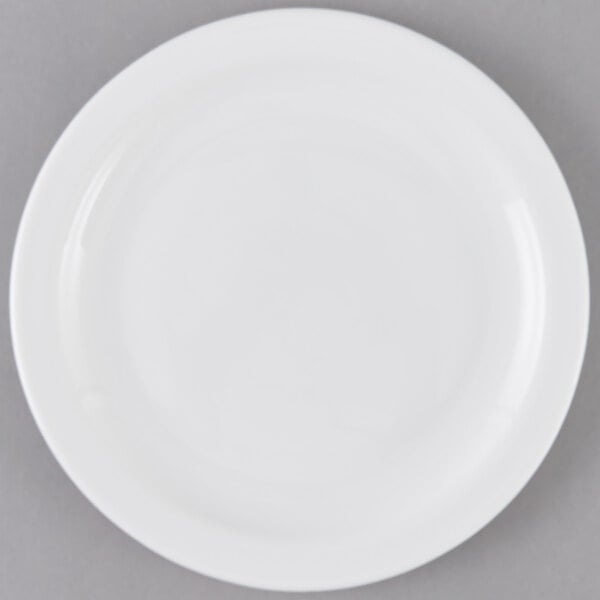 An Arcoroc white opal glass lunch plate with a white rim on a gray surface.