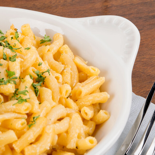 A Tuxton eggshell white round shirred egg dish filled with macaroni and cheese.