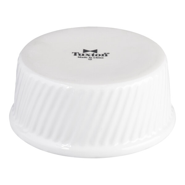 A white china souffle or ramekin with swirl sides, shown upside down.