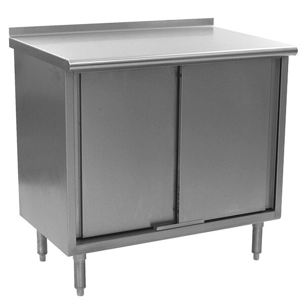 A stainless steel cabinet with two doors on a stainless steel work table.