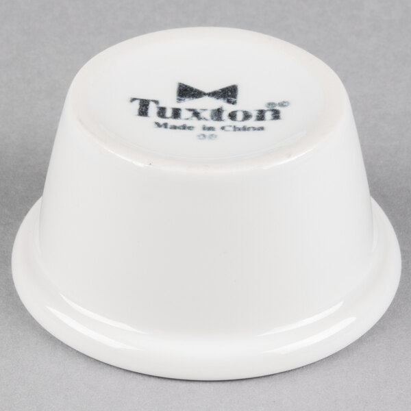 A white Tuxton China ramekin with black text.