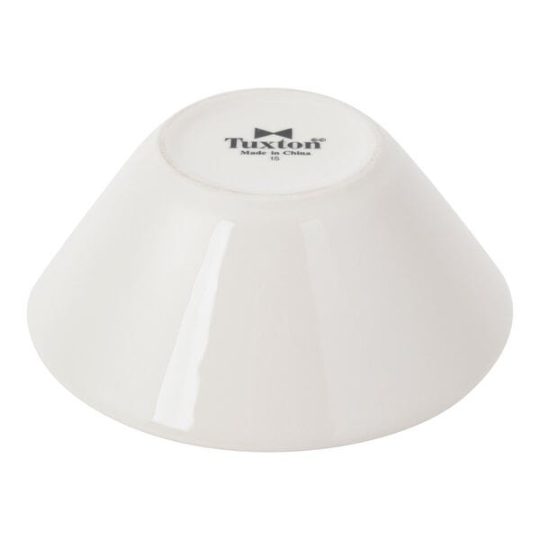 A white, tapered china bowl shown upside down with the Tuxton brand name on the bottom.