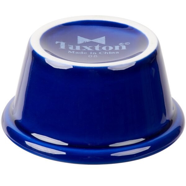A cobalt blue Tuxton china ramekin with white text on the side.