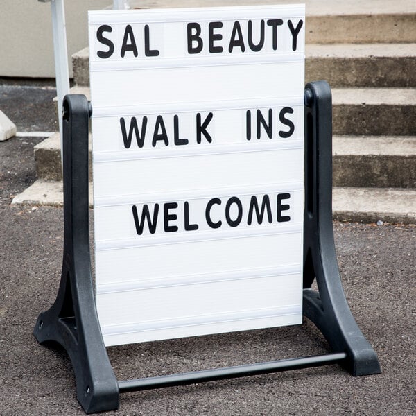 An Aarco white economy letterboard on a stand with two signs.