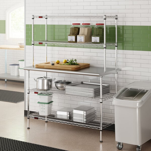 A stainless steel table with two chrome wire undershelves and two chrome wire overshelves, used for kitchen storage and prep.