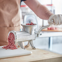 Manual aluminum meat grinder being used to grind meat