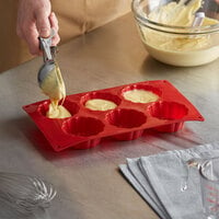 baker scooping batter into brioche mold