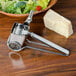 A cheese grater next to a bowl of salad with broccoli and lettuce.
