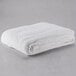 A white Oxford twin size hotel blanket folded up on a gray surface.
