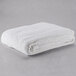 A folded white Oxford king size thermal herringbone hotel blanket on a gray surface.