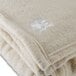 A close up of a white Oxford 100% polyester fleece blanket with white embroidery.