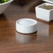 An American Metalcraft white porcelain salt dish on a table next to a bowl of salad.