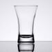 An Arcoroc clear shot glass on a reflective surface.