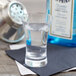 An Arcoroc shot glass filled with liquid on a napkin.