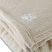 A close up of an Oxford vanilla fleece blanket with white embroidered logo.