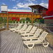 A case of white plastic Grosfillex Bahia chaise lounges on a deck.