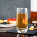 A close-up of a glass of liquid on a table with nuts and berries.