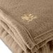 A close-up of a desert tan fleece Oxford hotel blanket.