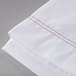 A close up of a white Oxford T200 Superblend XL Twin Size flat sheet with red stitching.