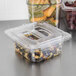 A Carlisle clear plastic food pan with fruit and vegetables in it on a counter.