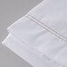 A close up of a white Oxford T200 Superblend king size flat sheet with gold stitching.