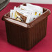 A maroon Tablecraft rectangle server with ridges holding packets on a hotel buffet counter.