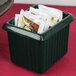 A Tablecraft hunter green cast aluminum rectangular server with ridges holding packets of condiments on a hotel buffet counter.