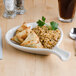 A Tuxton eggshell china fry pan server with brown rice on a table.