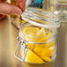 A person holding a Libbey Garden Jar filled with lemon slices.