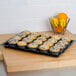 A Cal-Mil black bakery tray with blueberry muffins.