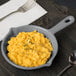 A Tablecraft granite cast aluminum fry pan of macaroni and cheese on a table.